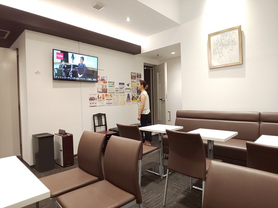 スタジオのロビーで教室の貼り紙を見るフルート奏者