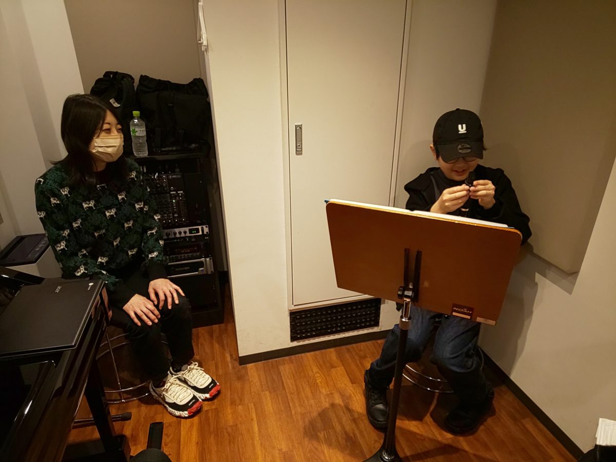 楽器の準備をする生徒とそれを見守るお母様