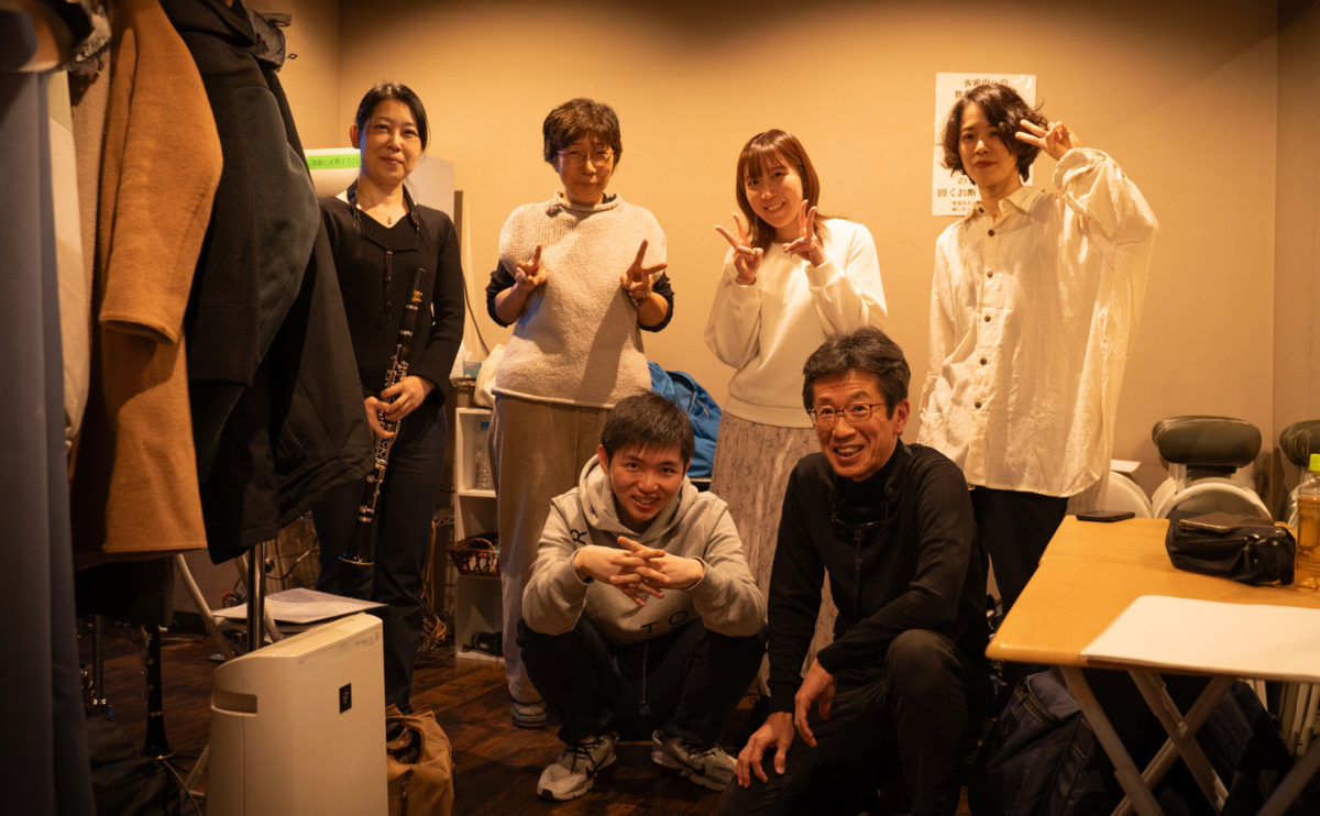 ライブハウスの楽屋で笑顔のバンドアンサンブルメンバー