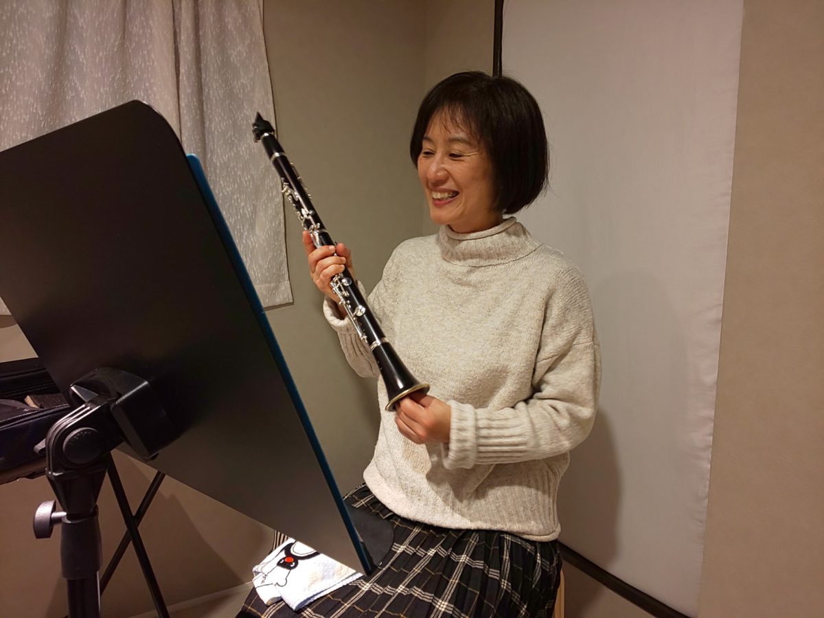 座って笑顔で楽器の掃除をする生徒