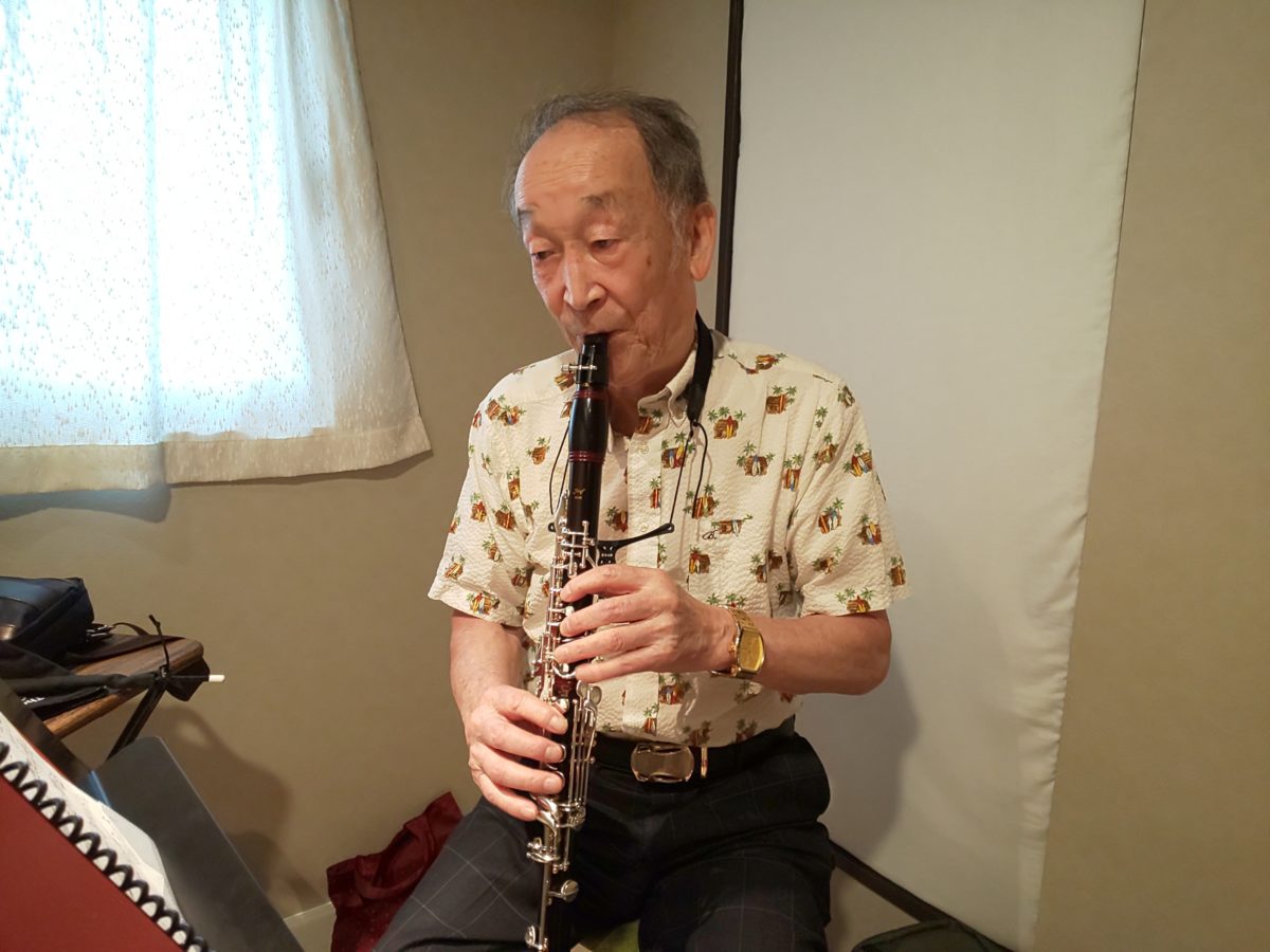 新しく購入したクラリネットを座って吹く生徒